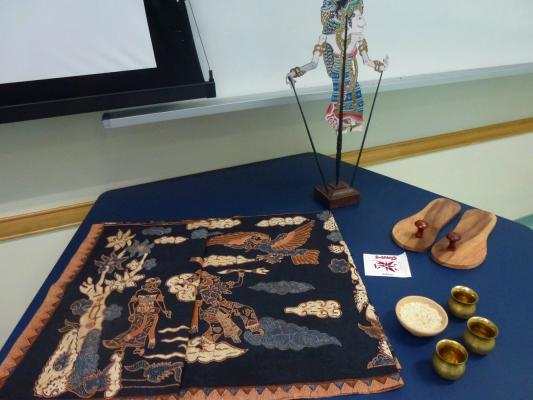 Kamini's unusual props for The Ramayana - antique Javanese batik story cloth, Indian wooden sandals, brass pots, Balinese shadow puppet of Sita, stick-on bindis for the audience